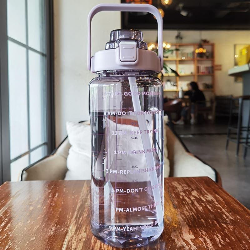 DFIT 2L transparent motivational bottle with lilac handle on a wooden café table